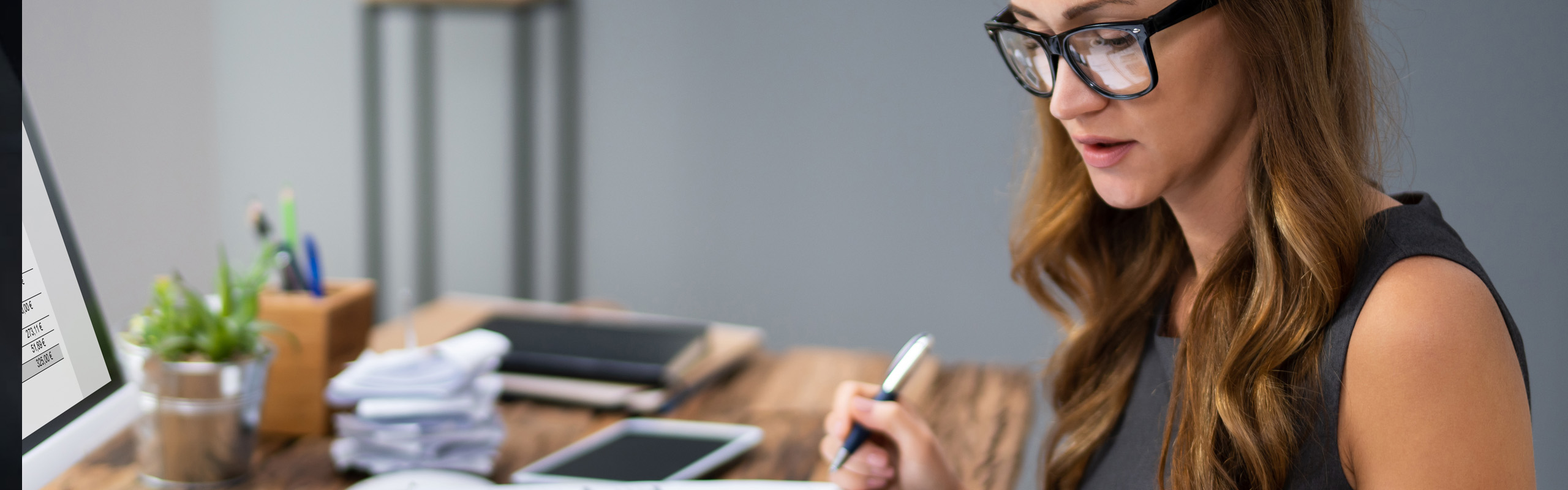 Eine Frau mit Brille arbeitet konzentriert an ihrem Laptop.
