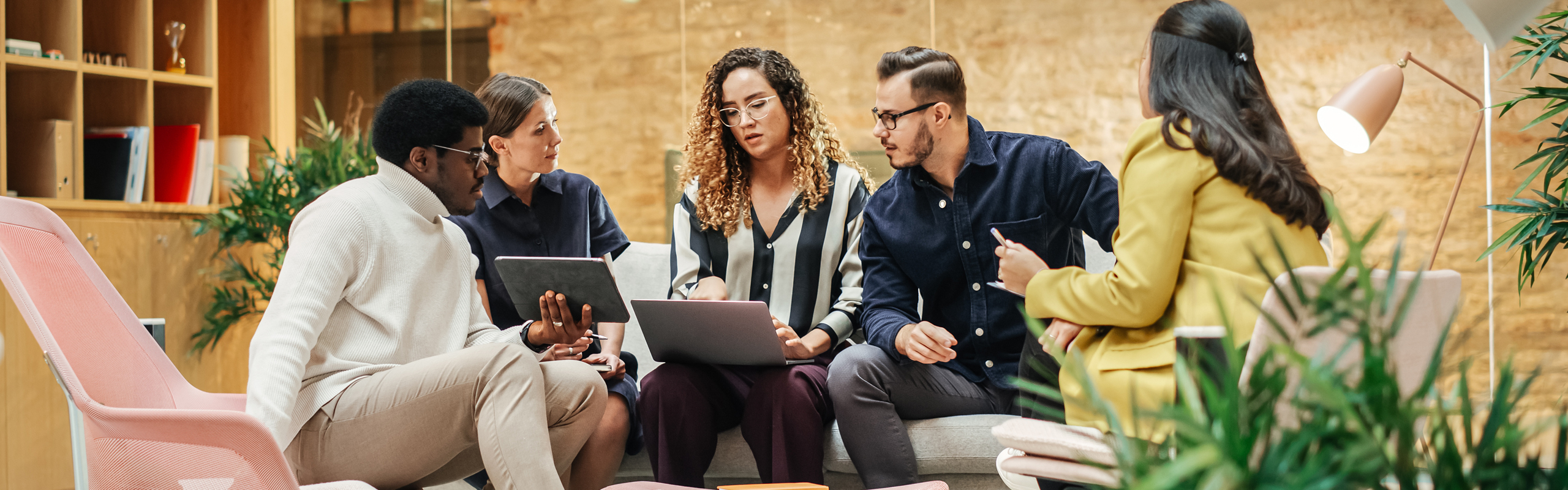 Mehrere Personen sitzen an einem Tisch, arbeiten an Laptops und tauschen Ideen aus.