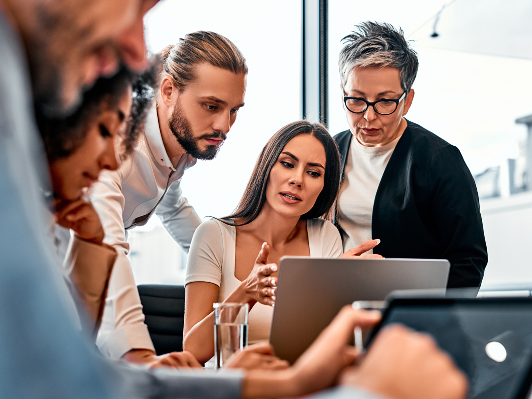 Mehrere Menschen betrachten einen Laptop in einer gemeinsamen Sitzung.