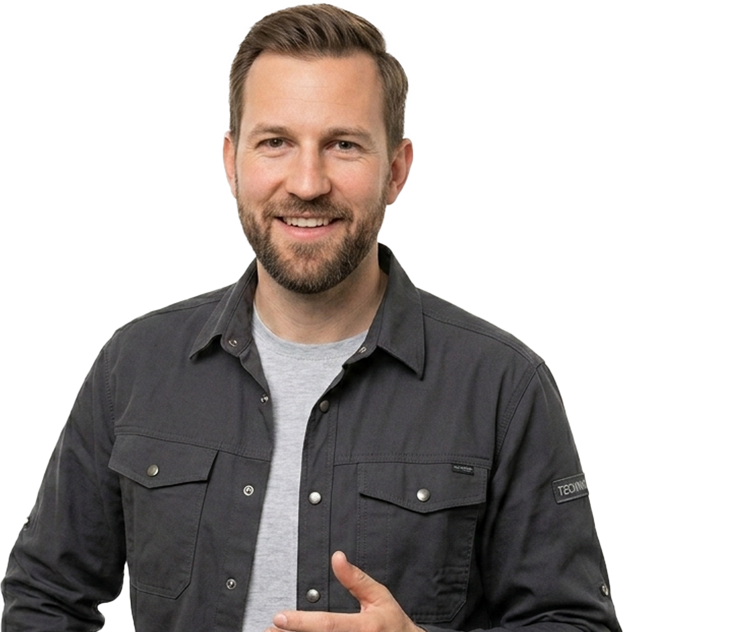 Smiling man in a dark button-up shirt over a gray tee against a white background, pointing with his right hand.