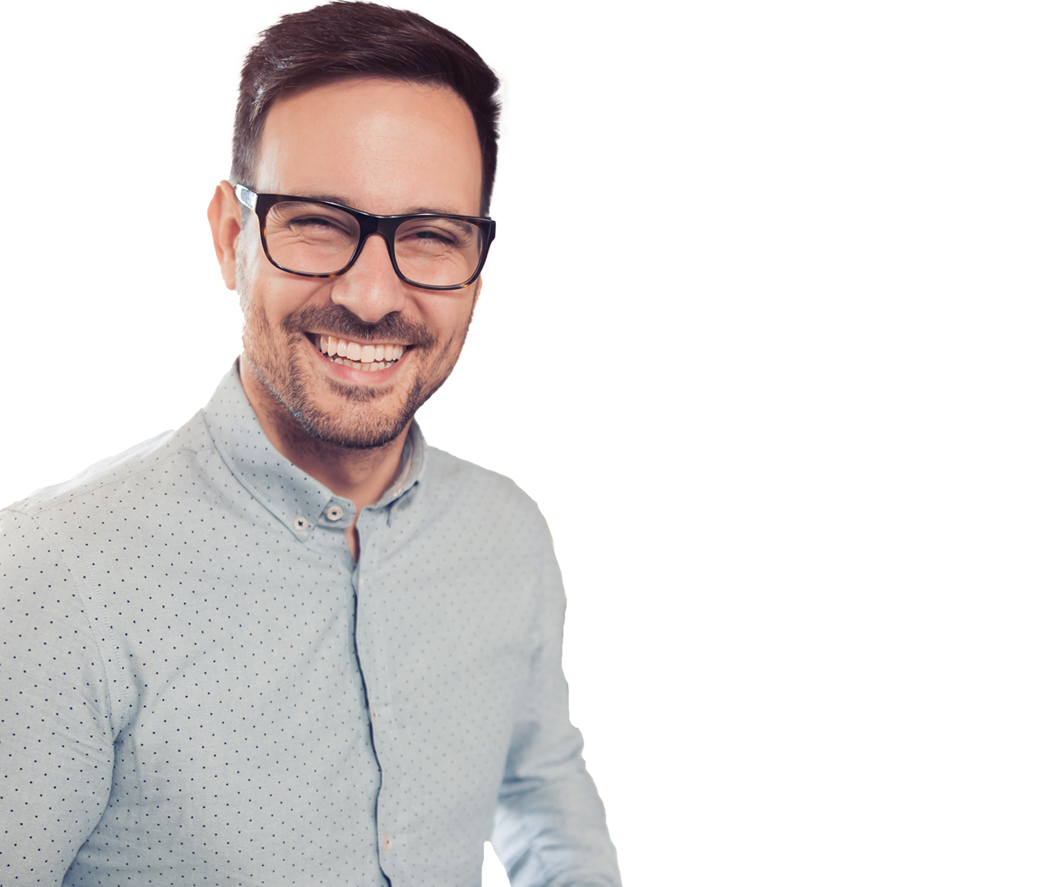 Smiling man with dark hair and glasses in a light dotted shirt indoors by a sunny window.